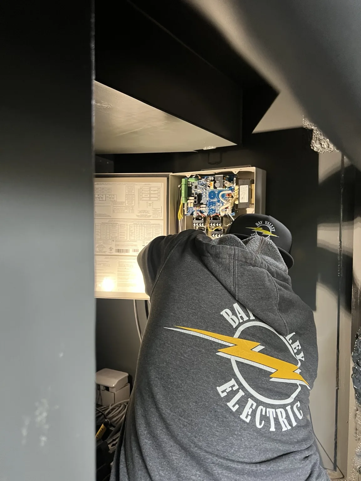 Bay Valley Electric branded clothing on an electrician working inside a property